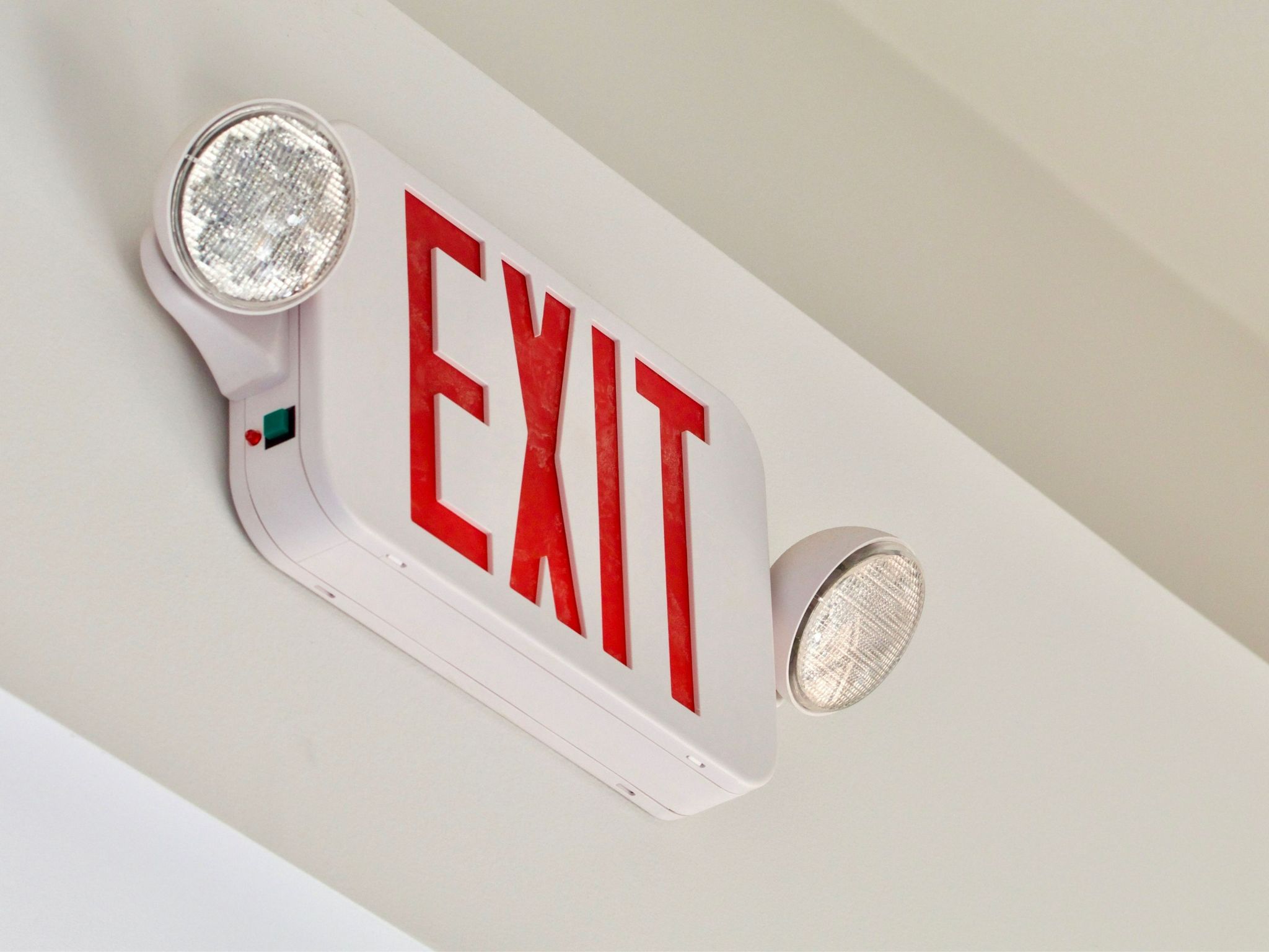 Red exit sign with emergency lights mounted on a ceiling