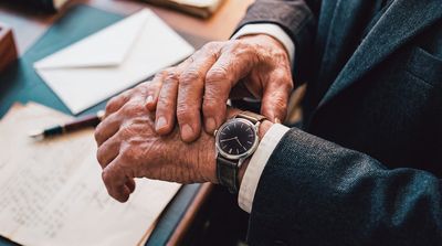 Experienced advisor's hands resting on documents at a wooden desk, fountain pen and papers nearby